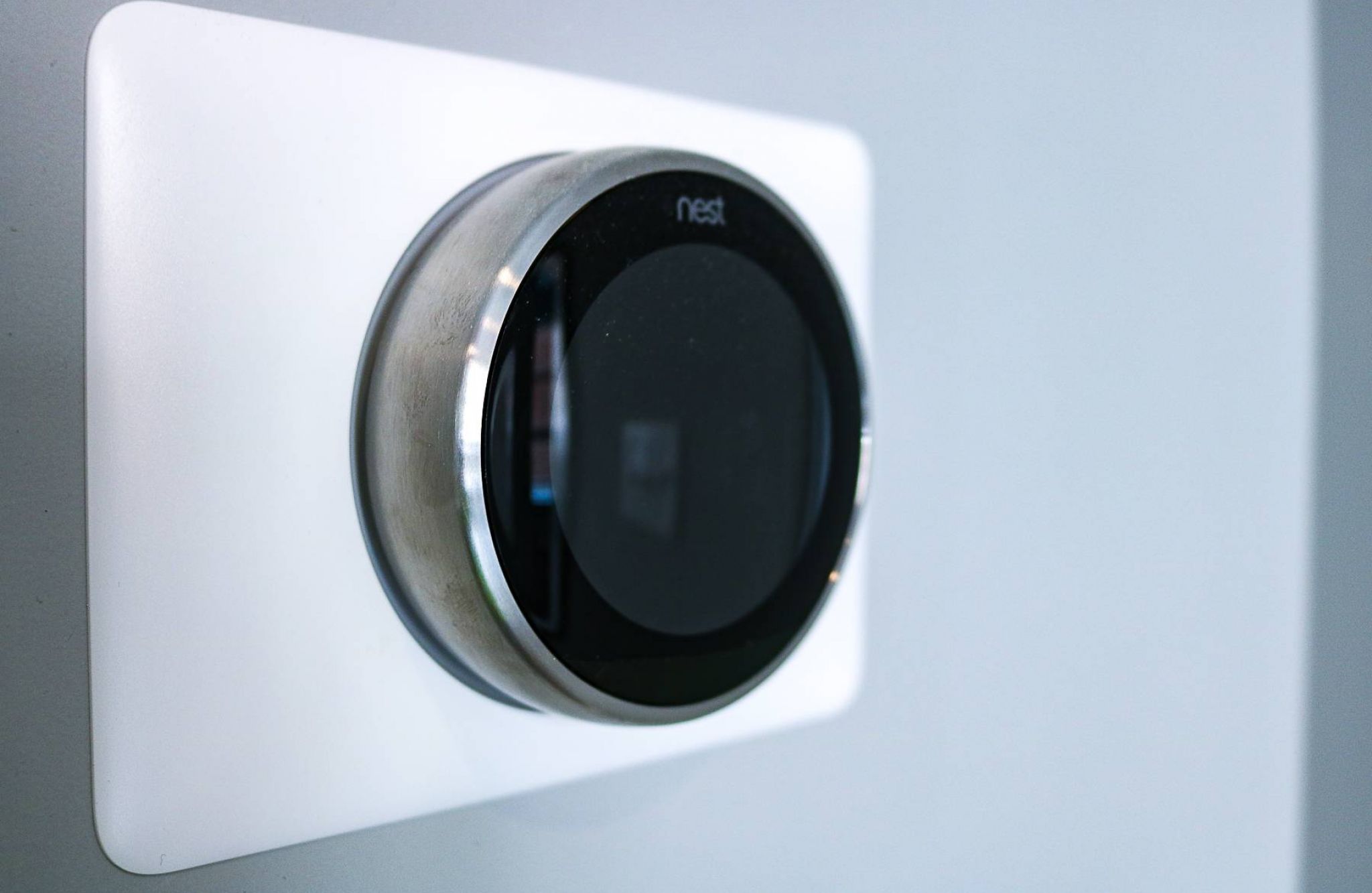 A Nest smart thermostat mounted on a light-colored wall.