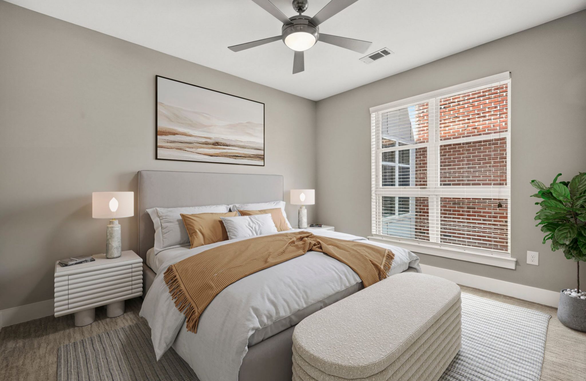 Modern bedroom with a bed, neutral bedding, two nightstands, lamps, wall art, plant, and large window with blinds.