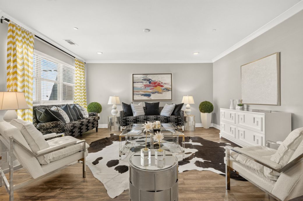 Modern living room with two sofas, armchairs, a cowhide rug, abstract art, and bright yellow curtains.